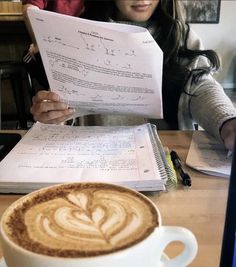 a woman sitting at a table with a cappuccino in front of her