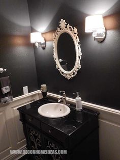 a white sink sitting under a bathroom mirror next to a black counter top with lights on it