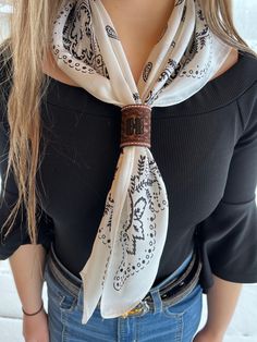 a woman wearing a black shirt and white scarf with a brown belt around her neck