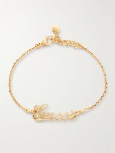 Gucci's bracelet is the perfect gift for a fan of the brand. It's been made in Italy from gold-tone metal and is centered with a script version of the house's moniker. Show it off with rolled cuffs or a sleeveless top. Luxury Gold-tone Bracelet With Logo Charm, Designer Metal Bracelets With Logo Charm, Luxury Gold-tone Jewelry With Logo Lettering, Yellow Gold Metal Jewelry With Gold-tone Logo, Designer Yellow Gold Jewelry With Logo Lettering, Designer Gold-tone Metal Bracelets, Designer Gold-tone Metal Bracelet, Formal Yellow Gold Jewelry With Gold-tone Logo Lettering, Gucci Yellow Gold Bracelet For Formal Occasions