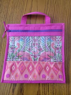 a pink and purple bag sitting on top of a wooden table next to a pair of scissors