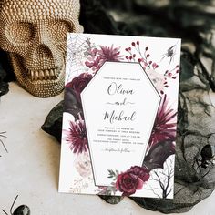 a wedding card with flowers on it next to a skull