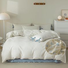 a bed with white sheets and blue bows on the comforter is in a bedroom