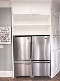 a refrigerator and freezer combo in a kitchen with white cabinets, wood floors and gray walls