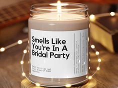 a candle is sitting on a table with some lights around it that says smells like you're in a bridal party