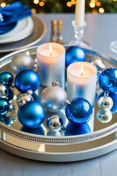 blue and silver ornaments on a tray with candles