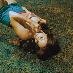 a woman laying on the grass with her legs spread out in front of her head