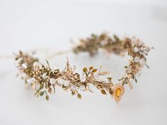 a crown made out of flowers and leaves on a white surface with no one around it