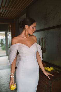 a woman in a white dress holding an apple