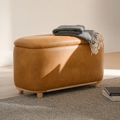 a tan leather ottoman sitting on top of a carpeted floor next to a book