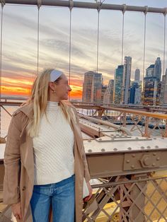 a woman standing on top of a bridge next to the ocean with buildings in the background