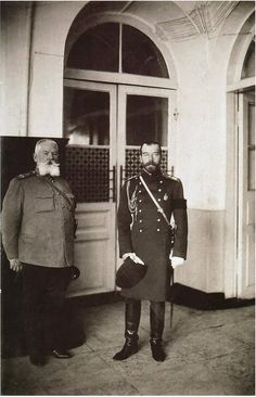 two men in uniform standing next to each other near a building with large doors and windows