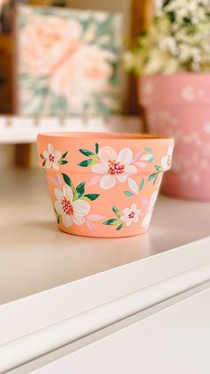 two pink flowered bowls sitting on top of a white dresser