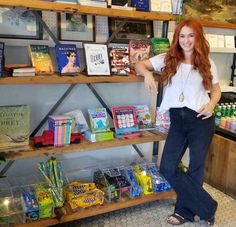 a woman standing in front of a book shelf filled with books