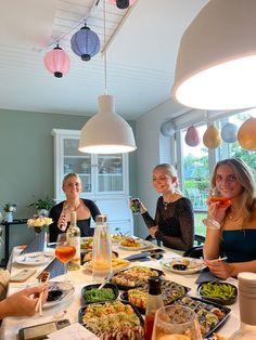 four women sitting at a table with plates of food and drinks in front of them