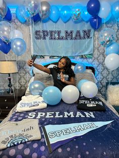 a woman sitting on top of a bed surrounded by blue and white balloons