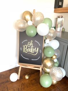 a chalkboard sign surrounded by balloons and confetti for a baby shower party