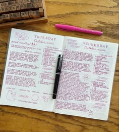 a pink pen sitting on top of an open notebook next to a rubber stamp and some type of calendar