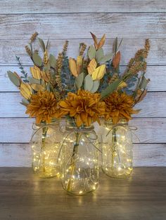 three mason jars filled with flowers and lights