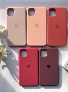 four iphone cases sitting next to each other on top of a white table with flowers