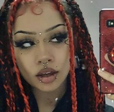 a woman with red dreadlocks taking a selfie in front of her phone