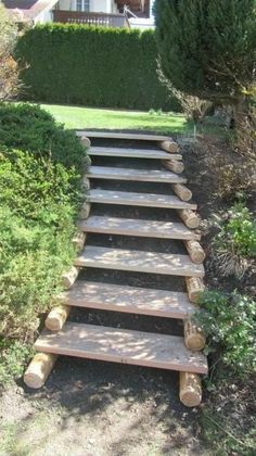 a set of steps made out of wood in front of a house with bushes and trees