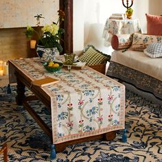 a living room with two couches and a table covered in a floral print cloth