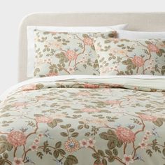 a bed with floral comforter and pillows on it