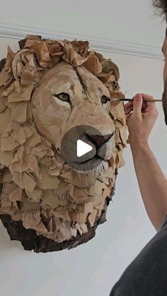 a man is making a paper mache of a lion's head on the wall