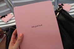 a person holding a pink book with the words little print book written on it in black