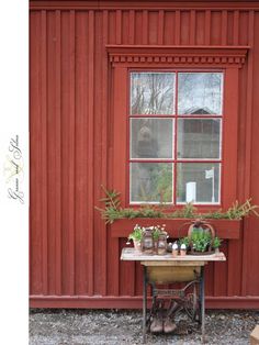 an old table with potted plants in front of a red building