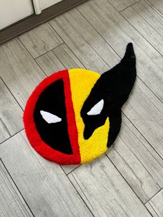 a deadpool rug is laying on the floor in front of a door with eyes