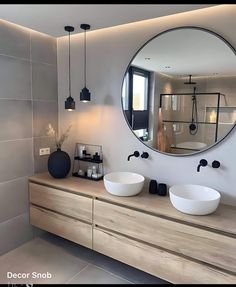 a bathroom with two sinks and a large round mirror on the wall above it's counter