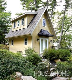 a small yellow house sitting on top of a lush green hillside