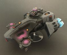 a toy space ship is shown on a black surface with pink and orange accents, as well as other toys