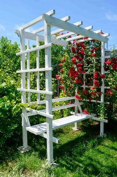 a white bench sitting in the middle of a lush green field with red flowers growing on it