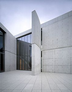 an empty building with two doors and windows on the outside, in front of a large concrete wall