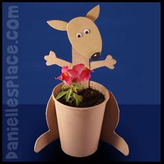 a cardboard kangaroo sitting on top of a potted plant with flowers in it's mouth