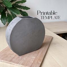 a cement vase sitting on top of a wooden cutting board next to a potted plant