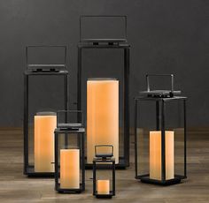 several lit candles are sitting in front of each other on a wooden floor with black frames