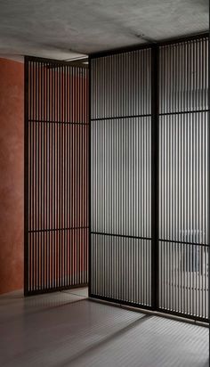 an empty room with wooden slats on the wall and concrete flooring in front of it