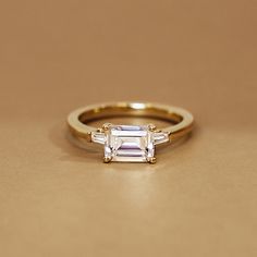 an engagement ring with three baguettes on the side, sitting on a table