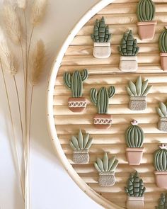 several small cactus plants are arranged on a round wooden board with some dried grass in the foreground