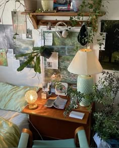 a desk with plants and pictures on the wall above it, along with a lamp