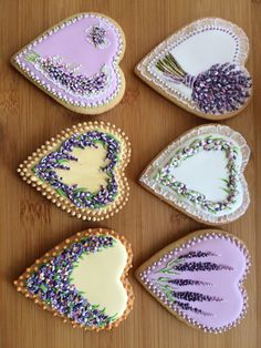 four decorated cookies with lavenders and hearts on them sitting on a table next to each other