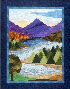 a quilted wall hanging with trees and mountains in the background, along with water