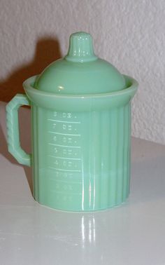 a green glass coffee pot sitting on top of a white counter next to a wall