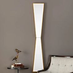 a white chair sitting next to a tall mirror on a wall near a table with a lamp