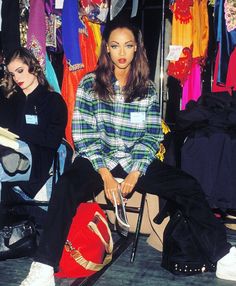 two women sitting on the ground in front of clothing racks