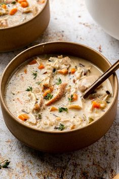 two bowls of chicken chowee with carrots and parsley on the side, next to a cup of soup